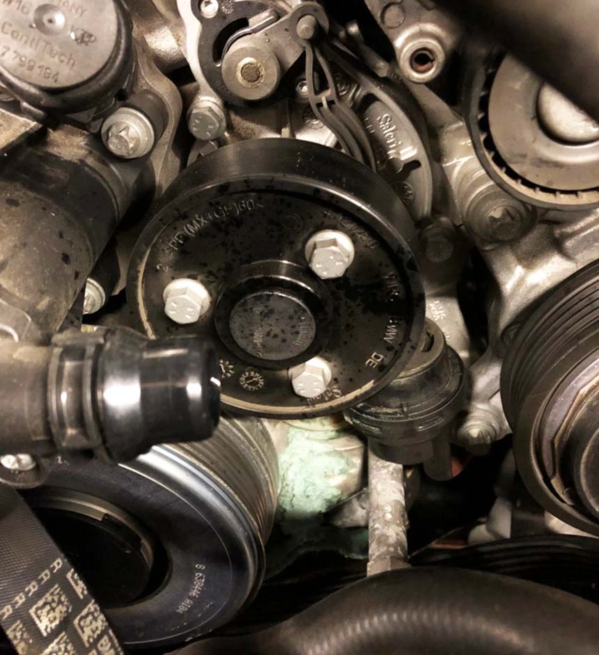 Une pompe à eau en panne sur un moteur BMW B48.  Vous pouvez voir la fuite du liquide de refroidissement.